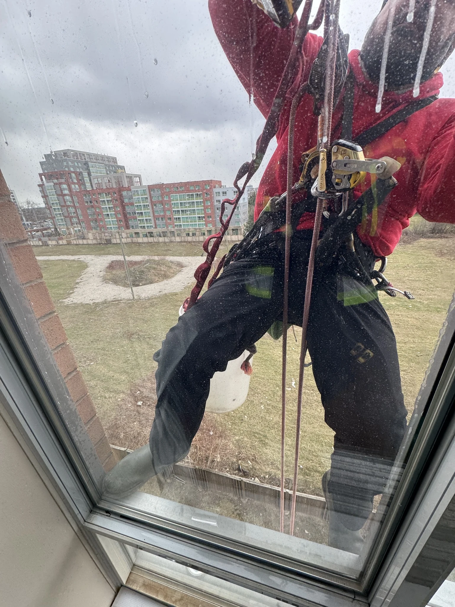 Rope-access glass technician performing an exterior window repair